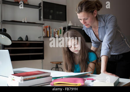 La madre ad assistere la figlia a fare i compiti a tavola Foto Stock