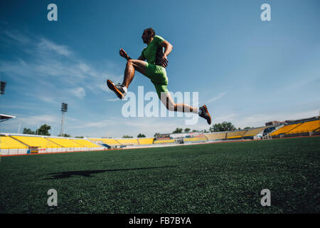 Per tutta la lunghezza della giovane atleta maschio in esecuzione in stadium durante il corso di formazione Foto Stock