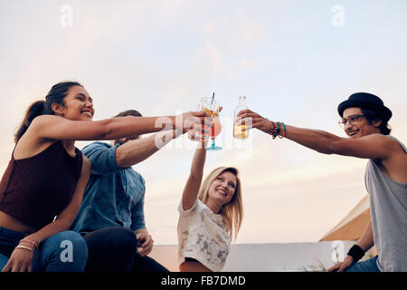 Happy amici per festeggiare il successo con un toast al partito sul tetto. Giovani uomini e donne cocktail di tostatura a parte. Giovani pers Foto Stock