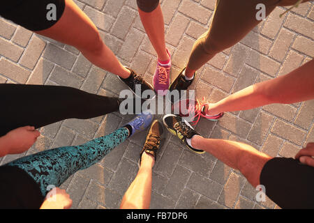 Le gambe degli atleti di indossare calzature sportive in un cerchio. Vista superiore di pattini in piedi insieme. Foto Stock
