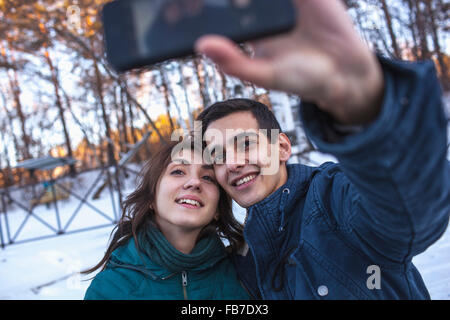 Felice coppia giovane tenendo selfie attraverso smart phone durante il periodo invernale Foto Stock