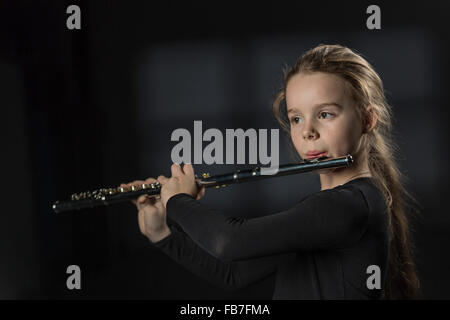 Ragazza carina la riproduzione di flauto su sfondo nero Foto Stock