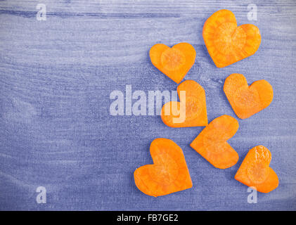Vintage cuore stilizzato realizzato di carota su sfondo di legno, lo spazio per il testo. Foto Stock