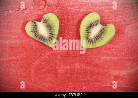 Cuori fatta di kiwi su sfondo di legno, lo spazio per il testo. Foto Stock