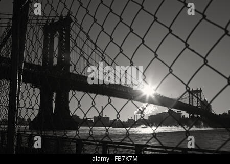 Distorta visione industriale di Manhattan Bridge waterfront New York City attraverso un filo guida di sicurezza. Bianco e nero, immagine in bianco e nero. Foto Stock