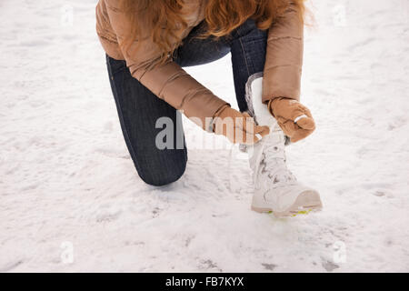 Energy-riempimento e eccitante weekend invernale in montagna. Primo piano sulla donna lacci delle scarpe di legatura in guanti all'aperto Foto Stock