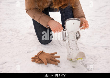 Energy-riempimento e eccitante weekend invernale in montagna. Primo piano sulla donna lacci delle scarpe di legatura senza guanti all'aperto Foto Stock