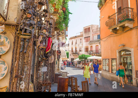 Shopping a Taormina Sicilia, in vista di una mezza età turista giovane guardando un display elaborati al di fuori di un negozio di antiquariato nel corso Umberto I. Foto Stock