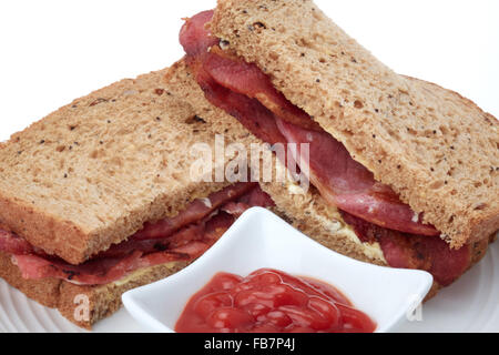 Un sandwich di bacon nel granaio pane marrone con alcuni tomato ketchup - studio shot con uno sfondo bianco. Foto Stock