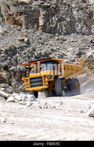 Un enorme camion caricato con eiettato roccia comincia il suo lungo viaggio verso la parte superiore della fossa dove la pietra sarà poi schiacciato. Foto Stock