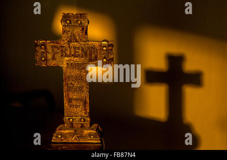 Una croce cristiana nei primi giorni di sole del mattino, getta un ombra sul muro. Foto Stock