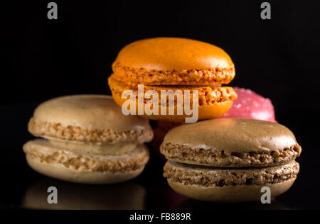 Francese amaretti colorati, giacente su sfondo nero Foto Stock