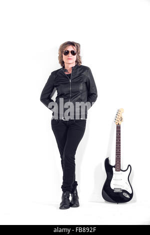 Musicista vestito in pelle nera sul muro bianco Foto Stock