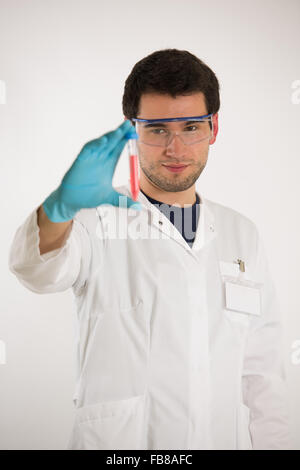 Ai giovani scienziati, indossando il camice bianco e guanti blu, sostiene il tubo con liquido colorato Foto Stock