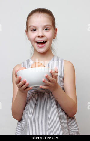 Allegro poco ragazza con vaso in ceramica con le uova organiche Foto Stock