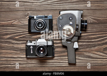 Retrò fotocamera reflex, telemetro e meccanica movie camera sul vecchio sfondo di legno Foto Stock
