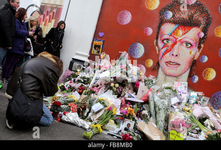 Londra, Gran Bretagna. Xii gen, 2016. I fan di pagare i loro aspetti con fiori e messaggi alla David Bowie murale di Brixton, Sud Londra, Gran Bretagna, a gennaio 12, 2016. Credito: Han Yan/Xinhua/Alamy Live News Foto Stock