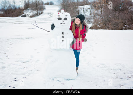 Pupazzo di neve e la bambina nella stagione invernale Foto Stock