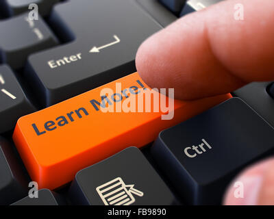 Un dito preme il pulsante arancione per saperne di più su nero della tastiera del computer. Primo piano. Messa a fuoco selettiva. Foto Stock