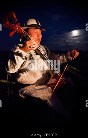 Una peli di cavallo fiddler e gola cantante convoglia i ritmi dei cavalli e la steppa la vita al chiaro di luna, Mongolia. Foto Stock