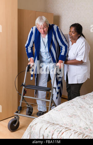 Anziani nonno in casa di cura utilizzando un rollator nel suo pigiama Foto Stock