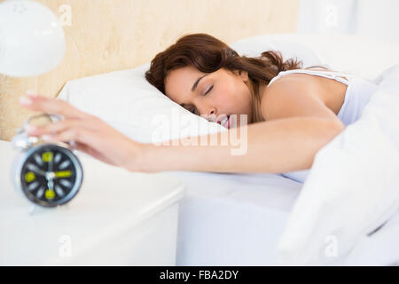 La donna addormentata fermando la sua sveglia Foto Stock