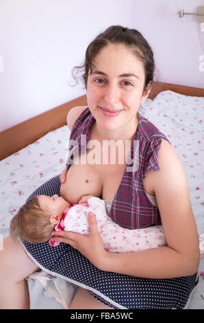 Felice madre allattamento neonato a casa Foto Stock