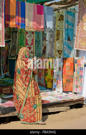 Donna indiana la vendita di tessuti colorati al mercoledì il mercato delle pulci a Anjuna beach a Nord Goa, India Foto Stock