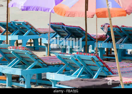 Righe del dipinto di spiaggia sdraio sulla spiaggia Aswem, Nord Goa, India Foto Stock