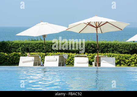 Sedie a sdraio e ombrelloni presso la piscina in Goa, India, Asia Foto Stock