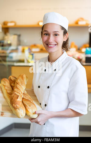 Vista di un giovane attarctive baker lavora presso la panetteria Foto Stock