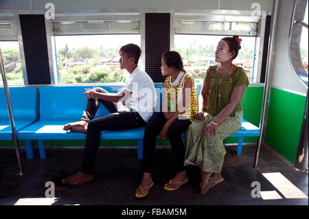 Madre birmano e i suoi due figli a sedersi in un vagone ferroviario guardando fuori dalla finestra a Rangoon in Myanmar Foto Stock