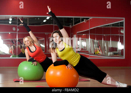 Due sorridenti ragazze sportiva stretching, facendo esercizi addominali su pilates fitballs Foto Stock