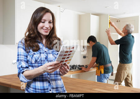 Donna che guarda la vernice grafico nella nuova cucina Foto Stock