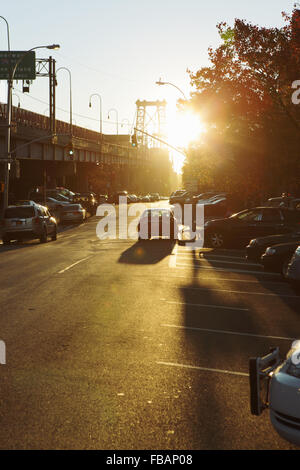 Visualizza in basso un Lower East Side backstreet dal Williamsburg Bridge come il sole sorge e razzi nella lente della fotocamera Foto Stock