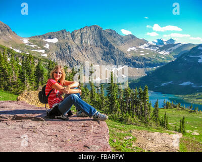 Giovane e sorridente di riposo turistico nel lago di nascosto si affacciano dopo un escursionismo. Il Parco Nazionale di Glacier, Montana, Stati Uniti. Foto Stock