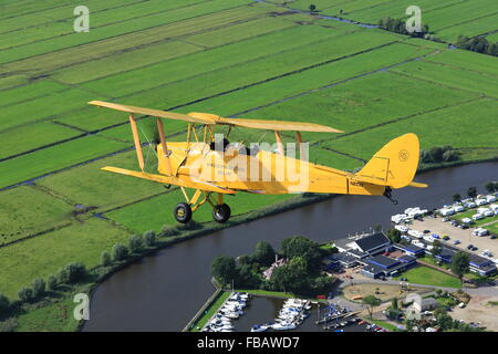 Un de Havilland Tiger Moth bi-piano oltre la campagna Olandese Foto Stock