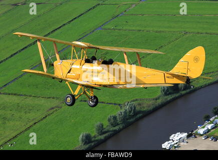 Un de Havilland Tiger Moth bi-piano oltre la campagna Olandese Foto Stock