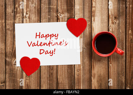 Valentines card con cuori rossi e la tazza di caffè sul tavolo in legno Foto Stock