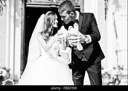 Happy sposi con le colombe a portata di mano la chiesa di sfondo Foto Stock