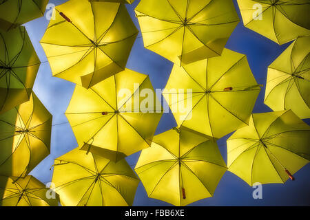 Basso angolo di Vista aprire gli ombrelli gialli sospesi in aria Foto Stock