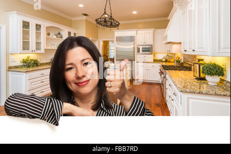 Donna ispanica con il pollice fino in cucina personalizzato interno su Pendente bianco. Foto Stock