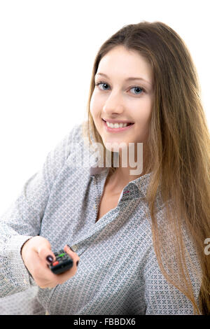 Allegro sorridente ragazza adolescente premendo il pulsante sul telecomando e cambiare i canali sul televisore, guardare film di commedia, zapping Foto Stock