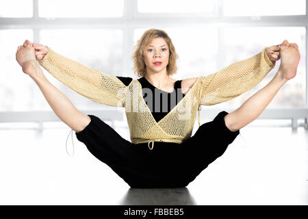 Sportivo da donna ballerino in classe lavoro fuori, facendo formazione di aerobica, riscaldamento, seduta gambe stretching Foto Stock