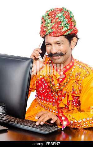 1 rurale indiano uomo Gujrati Computer di lavoro e telefono mobile multi-tasking Foto Stock