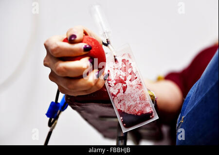 Dettaglio con la mano di un donatore di sangue la spremitura di una palla medica e una plastica sacca di sangue in un ospedale Foto Stock