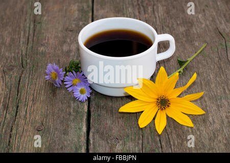 La tazza di caffè decorate in giallo e blu con fiori, su di un tavolo di legno Foto Stock