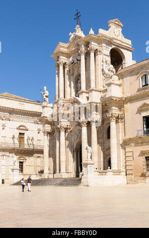 Un giovane a piedi attraverso la Piazza del Duomo di fronte alla facciata barocca della Cattedrale, Siracusa, Sicilia, Italia Foto Stock