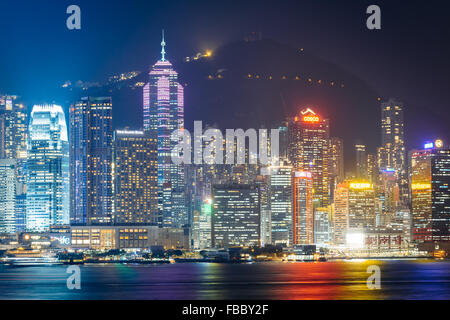 La skyline di Hong Kong e il Victoria Peak di notte, visto da Tsim Sha Tsui in Kowloon, Hong Kong. Foto Stock