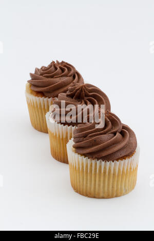 Tre tortini di cioccolato in una fila su un isolato sfondo bianco. orientamento verticale. Foto Stock